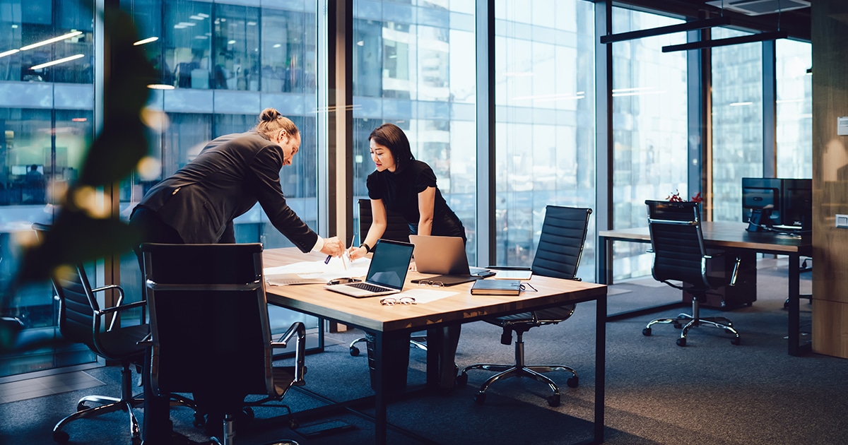 Colleagues working standing over desk