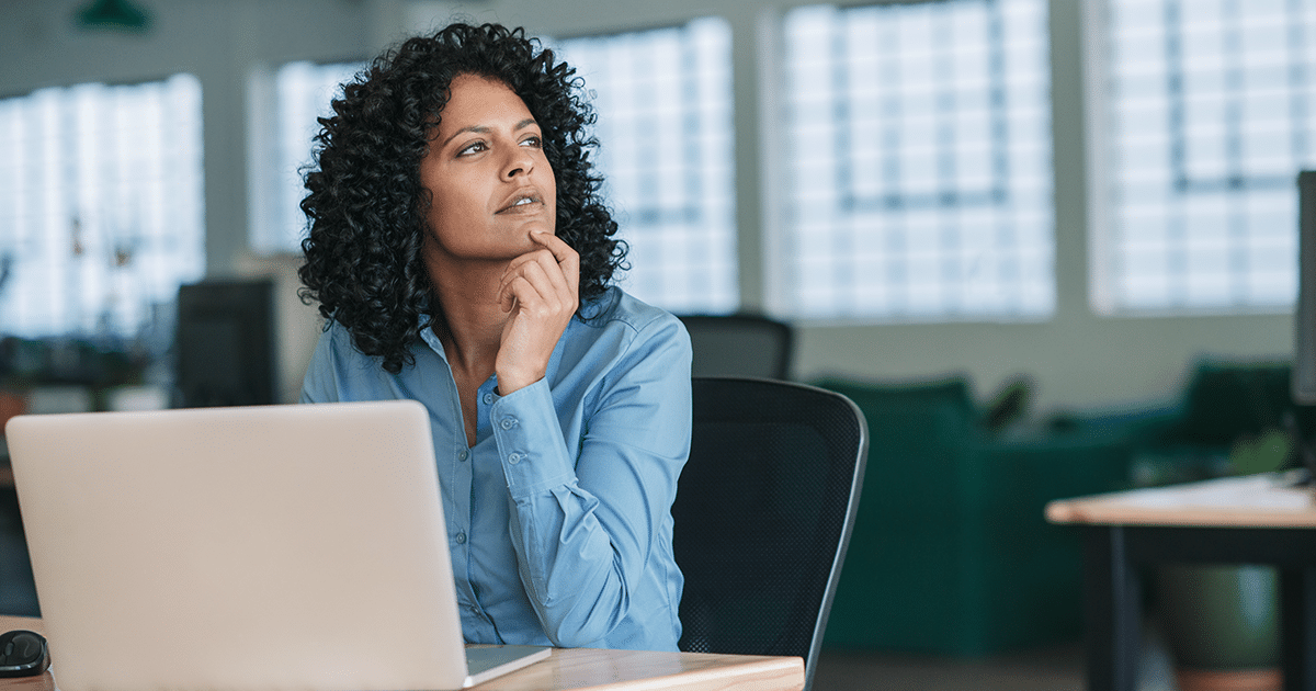 Frau arbeitet am Laptop und schaut in Gedanken weg