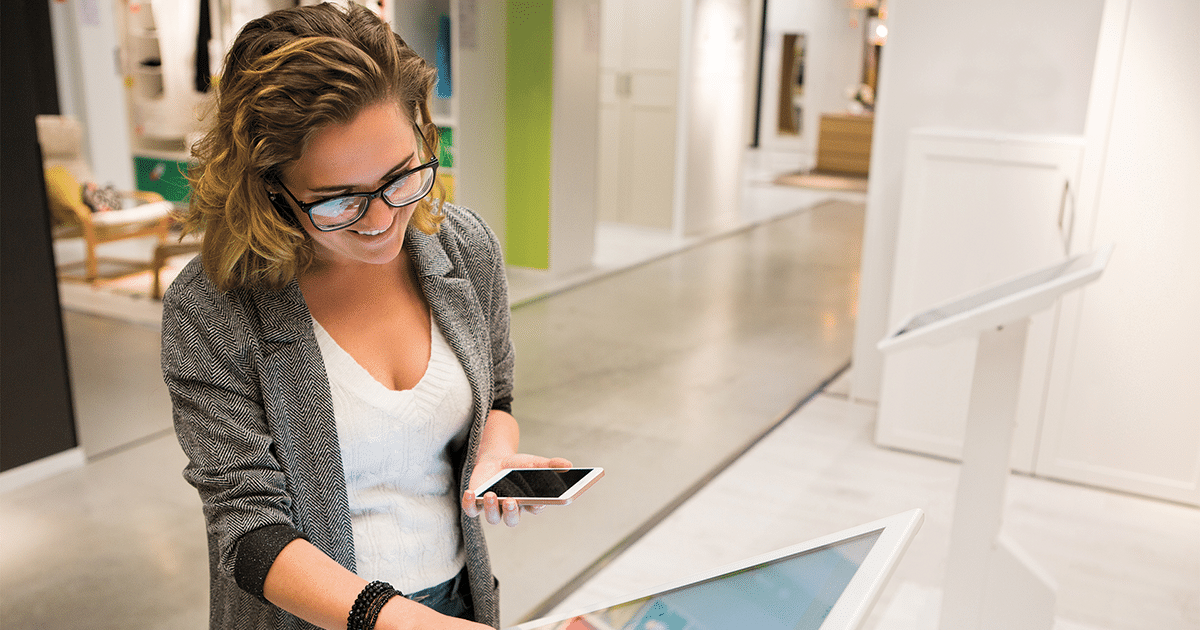 Lady holding her phone at a digital multy service kiosk.