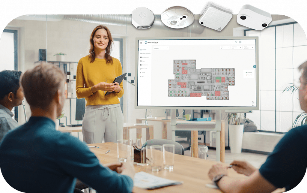 Mensen in vergadering met whiteboard dat real-time kantoorruimtebewaking toont